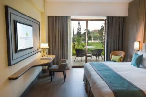 a hotel room with a bed and a desk and a window at Mason Pine Hotel Bandung in Padalarang