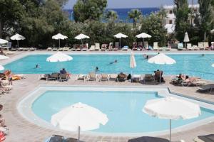 a large swimming pool with people in chairs and umbrellas at KOLYMBIA SKY HOTEL in Kolymbia