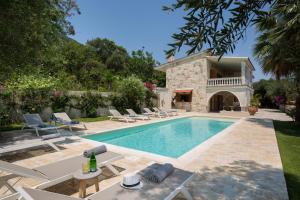 an outdoor swimming pool with chairs and a house at Ionian Garden Villas - Villa Pietra in Benitses