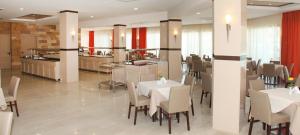 a restaurant with white tables and chairs and a kitchen at KOLYMBIA SKY HOTEL in Kolymbia