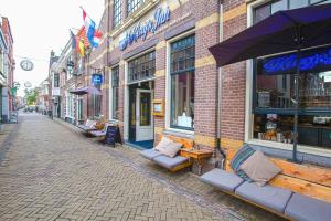 eine Kopfsteinpflasterstraße mit Bänken und Tischen vor einem Geschäft in der Unterkunft Kings Inn City Hostel in Alkmaar