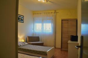 - une chambre avec un lit, une chaise et une fenêtre dans l'établissement Apartment D, à Zadar