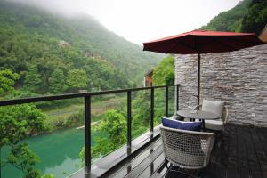 een balkon met een tafel en stoelen en uitzicht op een rivier bij AHN LAN Ninghai in Ninghai