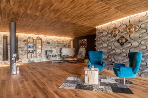 a living room with blue chairs and a stone wall at Boutique Hotel Kircher in Sarntal