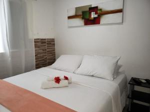 Una cama blanca con una caja con flores. en Casa da Albertina, en Fernando de Noronha