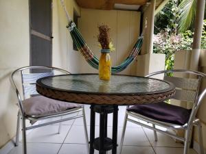 une table en verre avec deux chaises et un vase sur celle-ci dans l'établissement Casa da Albertina, à Fernando de Noronha