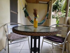 a glass table with two chairs and a vase on it at Casa da Albertina in Fernando de Noronha