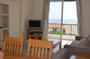 a living room with a couch and a television and a balcony at Caiti's Place in Paphos