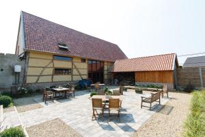 a patio with tables and chairs in front of a building at B&B 't Maanhof in Gingelom