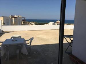 a table and chairs on a balcony with the view of the ocean at Penthouse avec vue imprenable sur mer in Chott Meriem