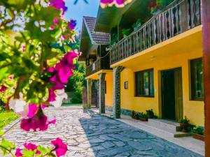 a cobblestone street next to a yellow building with pink flowers at Casa Ursu in Cîrţişoara