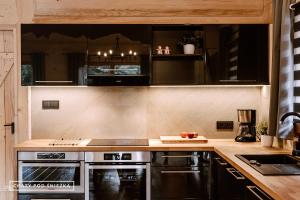 a kitchen with stainless steel appliances and black cabinets at Chaty pod Śnieżką in Karpacz