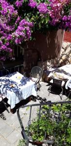 a table and chairs in a garden with purple flowers at Apartman i Sobe Čule Cres in Cres