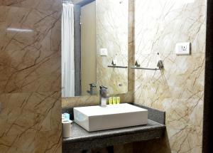 La salle de bains est pourvue d'un lavabo blanc et d'un miroir. dans l'établissement Hotel City Inn, à Varanasi