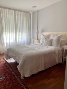 um quarto com uma cama grande e lençóis brancos em Plaza la Ria em Fonte Culler