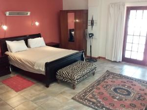 1 dormitorio con 1 cama y un taburete de cebra en Blue Haze Country Lodge, en Estcourt