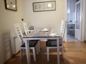 mesa de comedor con sillas blancas, mesa, mesa y sillón en Bermejo Apartamento, en Candás