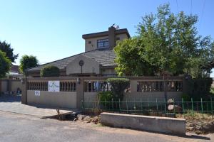 a house with a fence in front of it at Triple Palms Bed and Breakfast in Gaborone