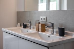 a white bathroom with two sinks and a mirror at Hotel Rosenhof in Kühlungsborn