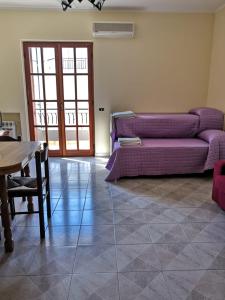 ein Wohnzimmer mit einem lila Sofa und einem Tisch in der Unterkunft Appartamento A due passi dal mare in Caulonia Marina