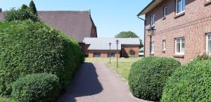 a walkway in front of a brick house with bushes at Gästehaus Höltig in Havekost