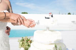 Una novia y un novio cortando su pastel de bodas en la playa en Osteria dei Segreti, en Appignano