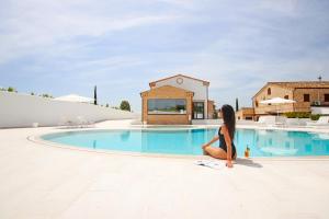 a woman sitting next to a swimming pool at Osteria dei Segreti in Appignano