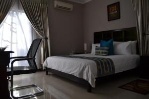 a bedroom with a bed with a chair and a window at Triple Palms Bed and Breakfast in Gaborone