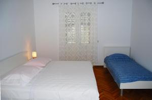 a bedroom with a white bed and a window at Rooms&Apartments Jerka in Supetar