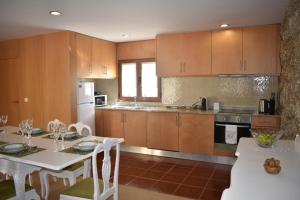 una cocina con armarios de madera y una mesa blanca con sillas. en Quinta do Perguntouro, en Barrosas