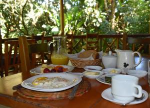 a table with plates of breakfast food and a pitcher of orange juice at El Descanso in Mindo
