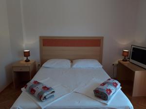 a bedroom with a white bed with two pillows on it at Apartments Renata in Rab
