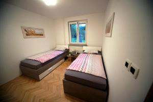 Duas camas num pequeno quarto com uma janela em Apartment Arh em Bled