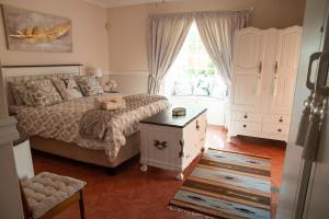 a bedroom with a bed and a dresser and a window at Roses and Pebbles B & B Guest House in Klerksdorp