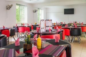 een eetkamer met tafels en stoelen met roze bogen bij Bilkon Hotel Jinja in Jinja