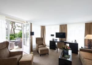 a living room with a couch and chairs and a television at Strandhotel Fontana in Timmendorfer Strand