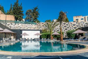 a large swimming pool with chairs and umbrellas at Landmark Amman Hotel & Conference Center in Amman
