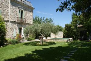an old stone house with a tree in the yard at Chambre Foret du Mas des Fontaines in Montagnac