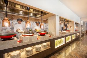 two chefs in a kitchen preparing food in a restaurant at Grupotel Parc Natural & Spa in Playa de Muro