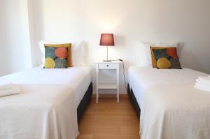 2 łóżka pojedyncze w pokoju z lampką na stole w obiekcie Parque das Nacoes River view ,free wifi w Lizbonie
