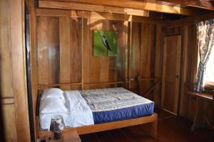 Cama pequeña en habitación con paredes de madera en El Descanso, en Mindo