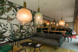 ein Restaurant mit einem Sofa, Tischen und Hängelampen in der Unterkunft Kitz Boutique Hotel & Restaurant in Metzingen