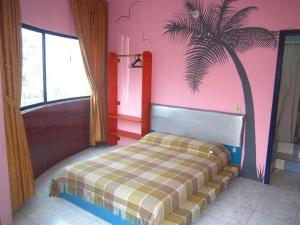 - une chambre dotée d'un lit avec un palmier sur le mur dans l'établissement La Casa Ucraniana, à Canoa