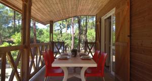 una mesa en el porche de una cabaña con sillas rojas en VVF Landes Moliets, en Moliets-et-Maa