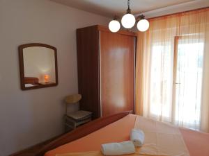 a bedroom with a bed with a mirror and a window at Apartments Renata in Rab