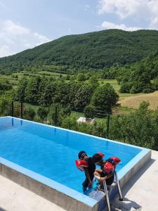 Deux personnes se tiennent à côté d'une piscine dans l'établissement Apartments Hills, à Ćukovi