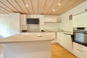cocina con armarios blancos y techo de madera en Ferienwohnung Stuiben en Blaichach