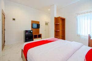 um quarto com uma cama vermelha e branca e uma televisão em Super OYO 13I9 88 Exclusive Guesthouse em Yogyakarta