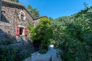 an old stone house with a red door and trees at Le mas des sources cevenol Le chambon in Le Chambon