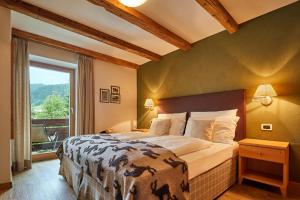 um quarto com uma cama grande e uma janela grande em Garni Karin em Corvara in Badia